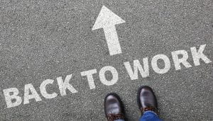 Back to Work Sign on the Road with an Arrow and Person’s Feet Towards It 