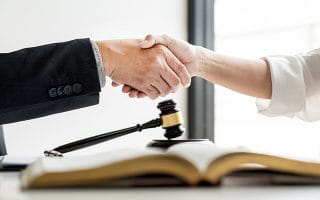 Two People Handshake over an Open Book and a Gavel